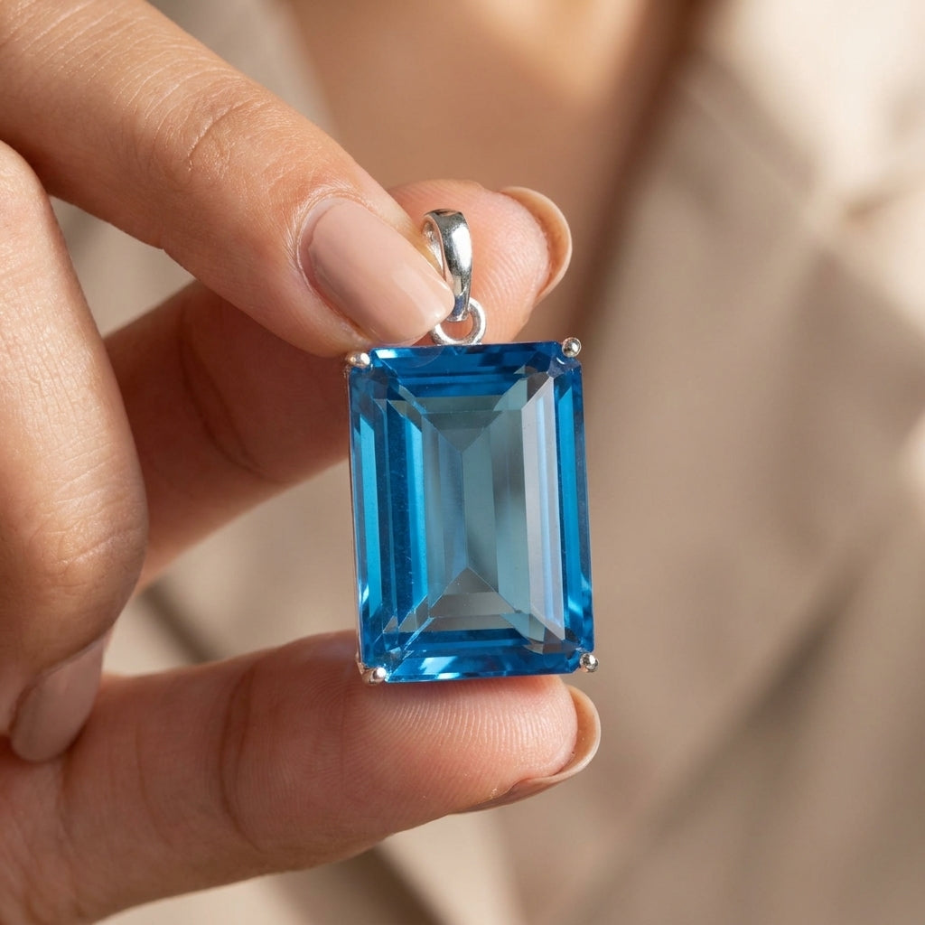 GEMHUB Blue Topaz Emerald 120 Ct pendant held in hand for size (AI)