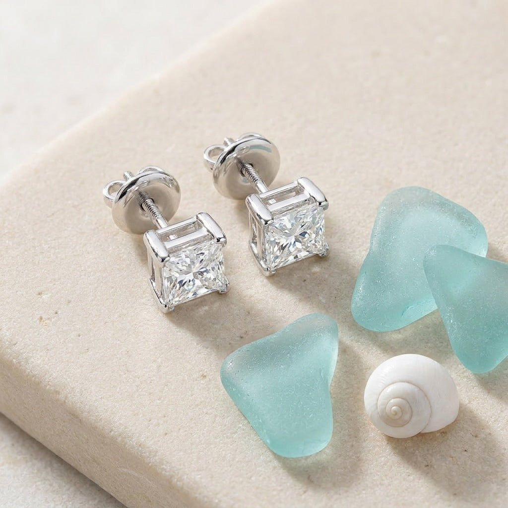 Diamond solitaire studs on a sea-glass flat-lay