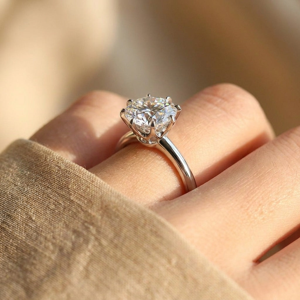 Close-up of round moissanite ring on finger showing tall prongs