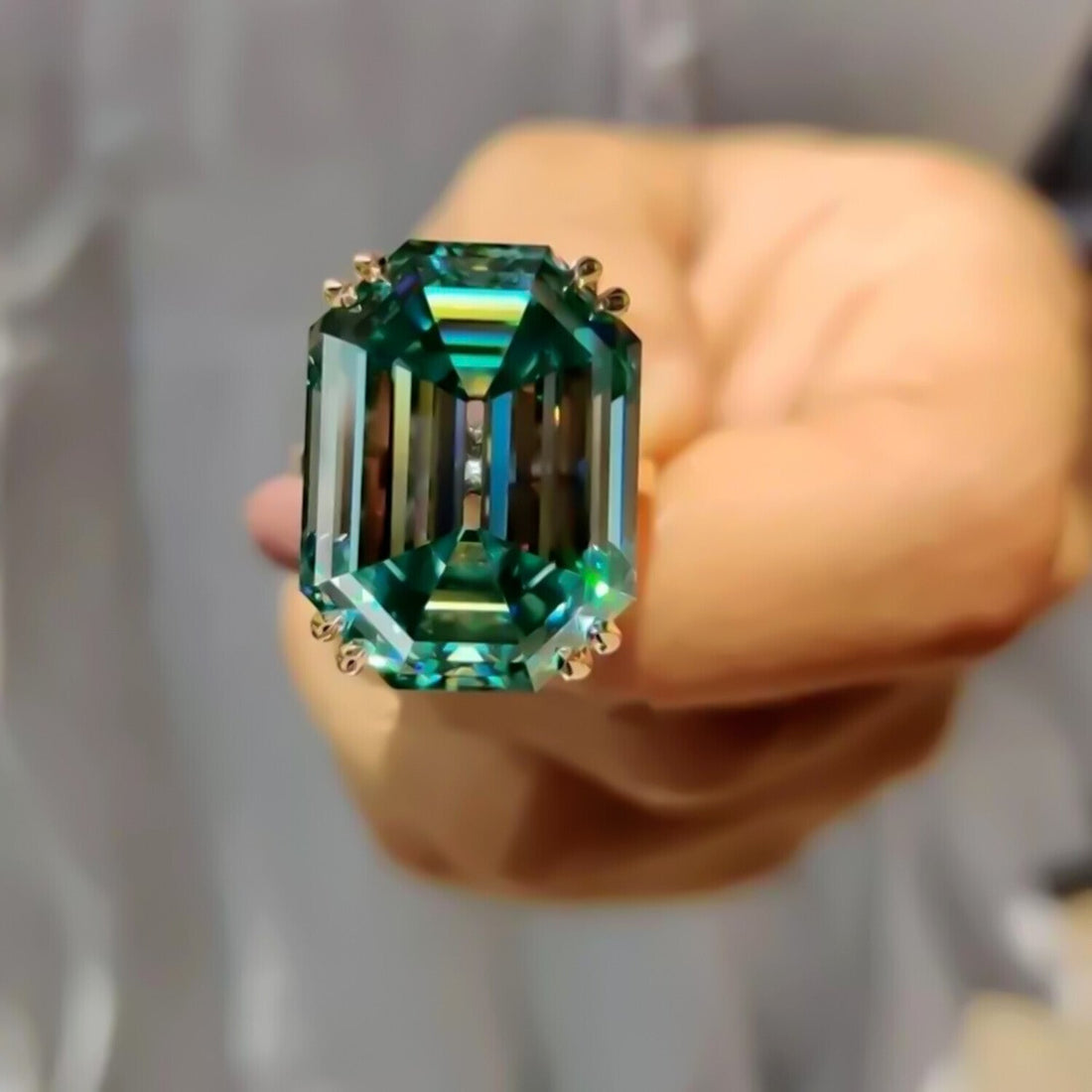 Lab grown green emerald solitaire ring, close-up of the emerald-cut stone and prongs – GEMHUB