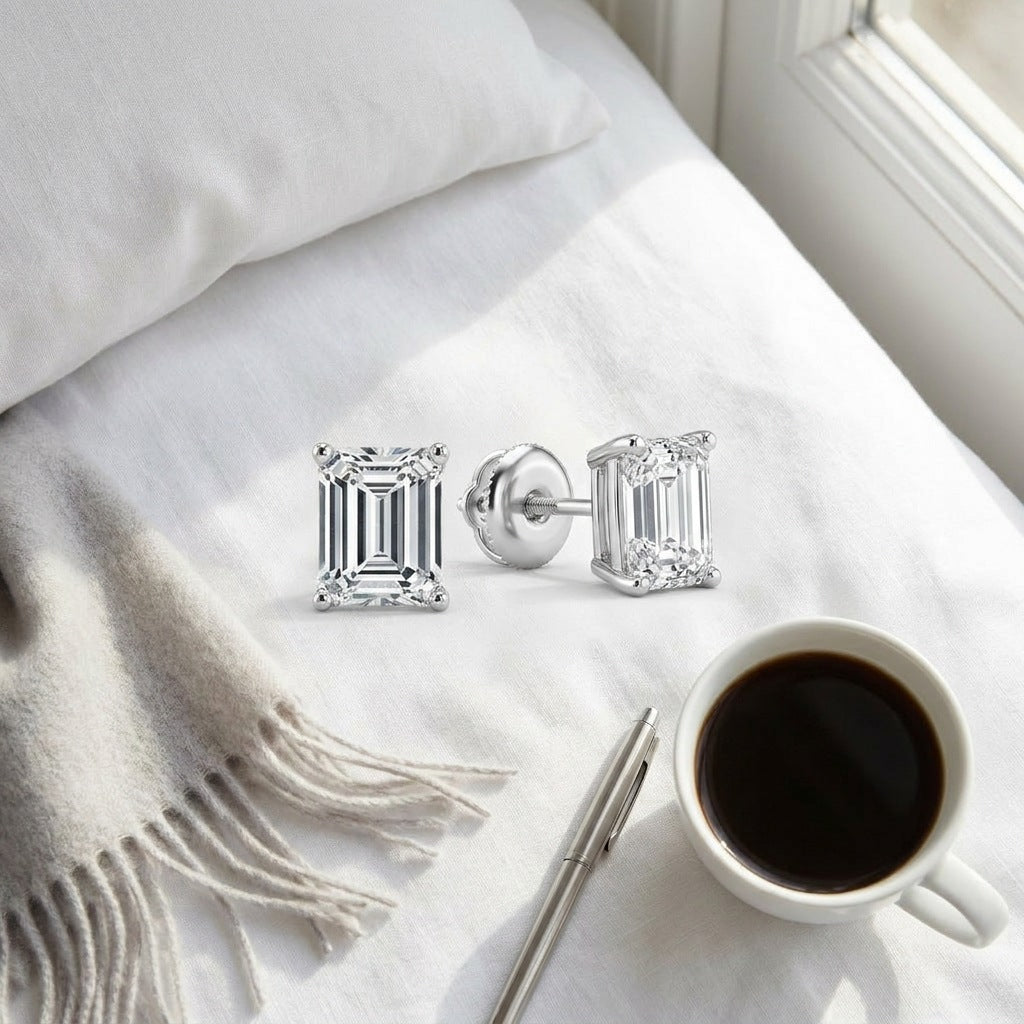 Emerald-cut diamond studs flat-lay on white linen
