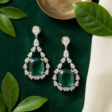 Emerald drop earrings flat-lay with silk and fresh leaves